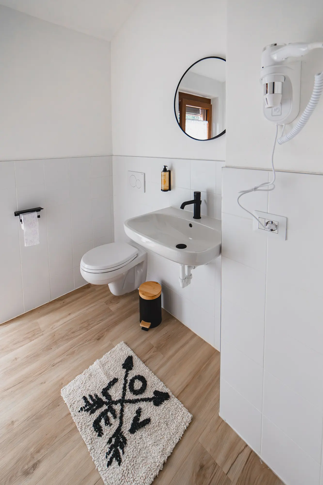 Clean, modern bathroom with sink, toilet, mirror, and hair dryer