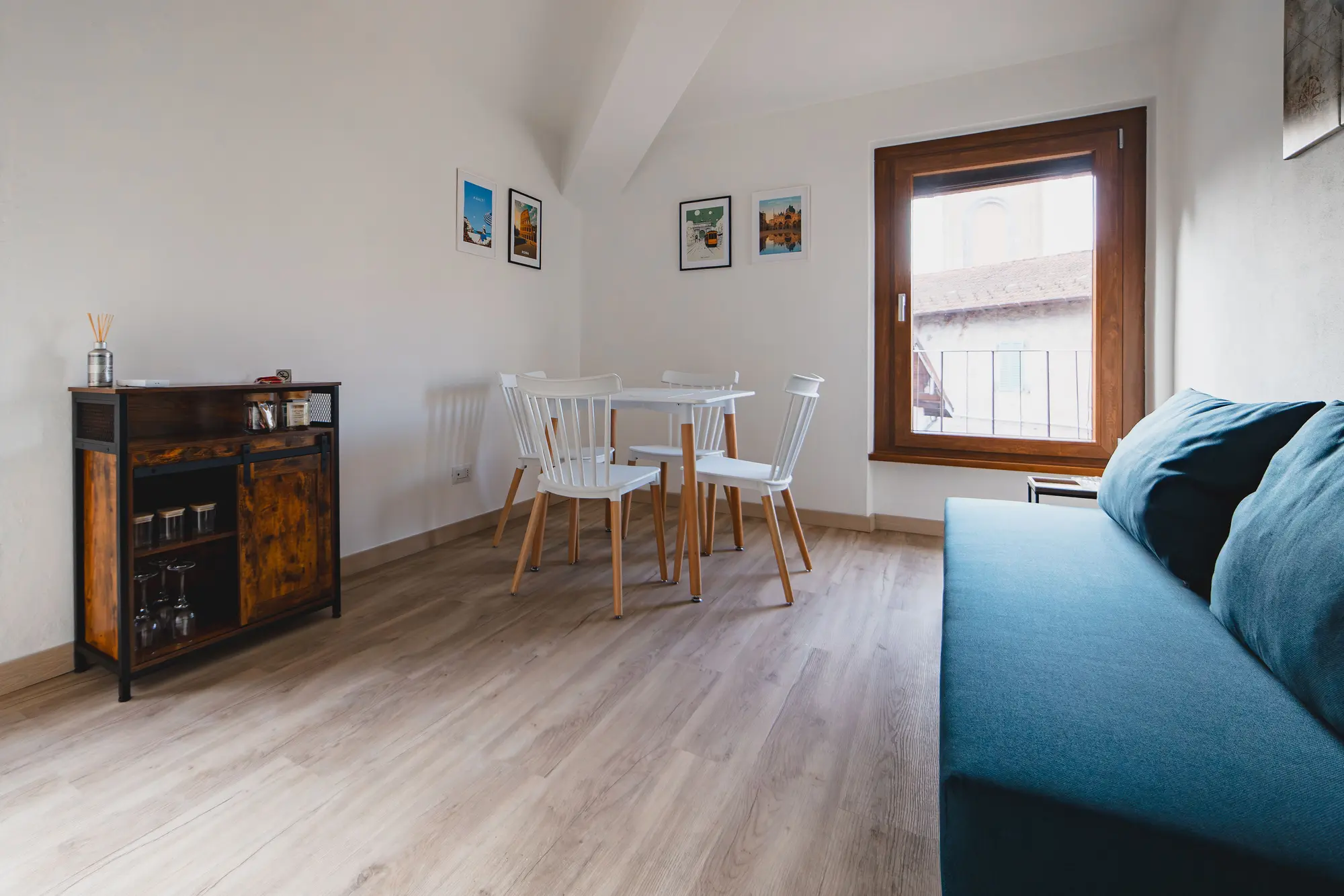 Living room with dining table, sofa bed, and large window letting in natural light