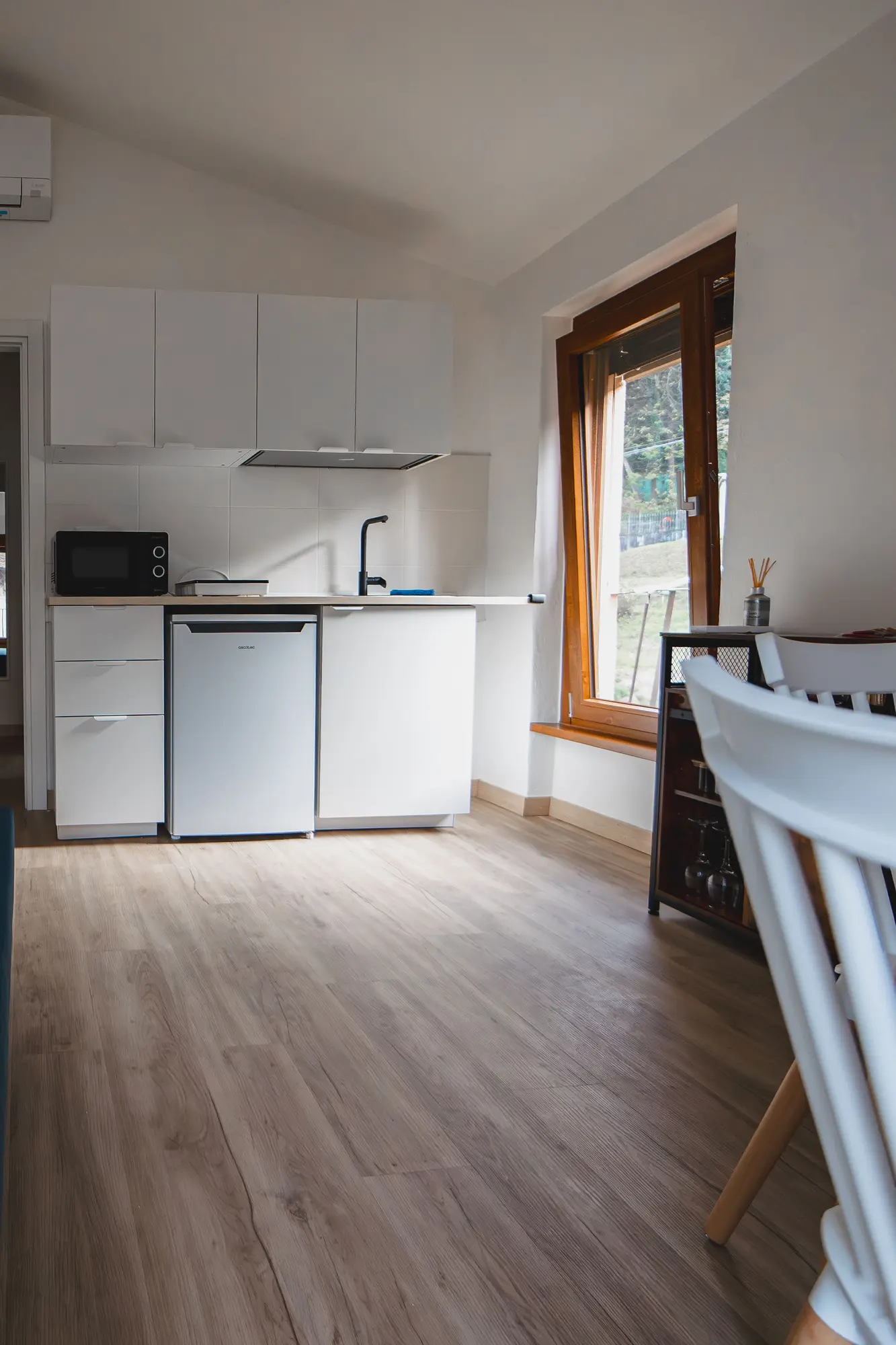 Bright living room with fully equipped kitchen, wooden floors, and natural light