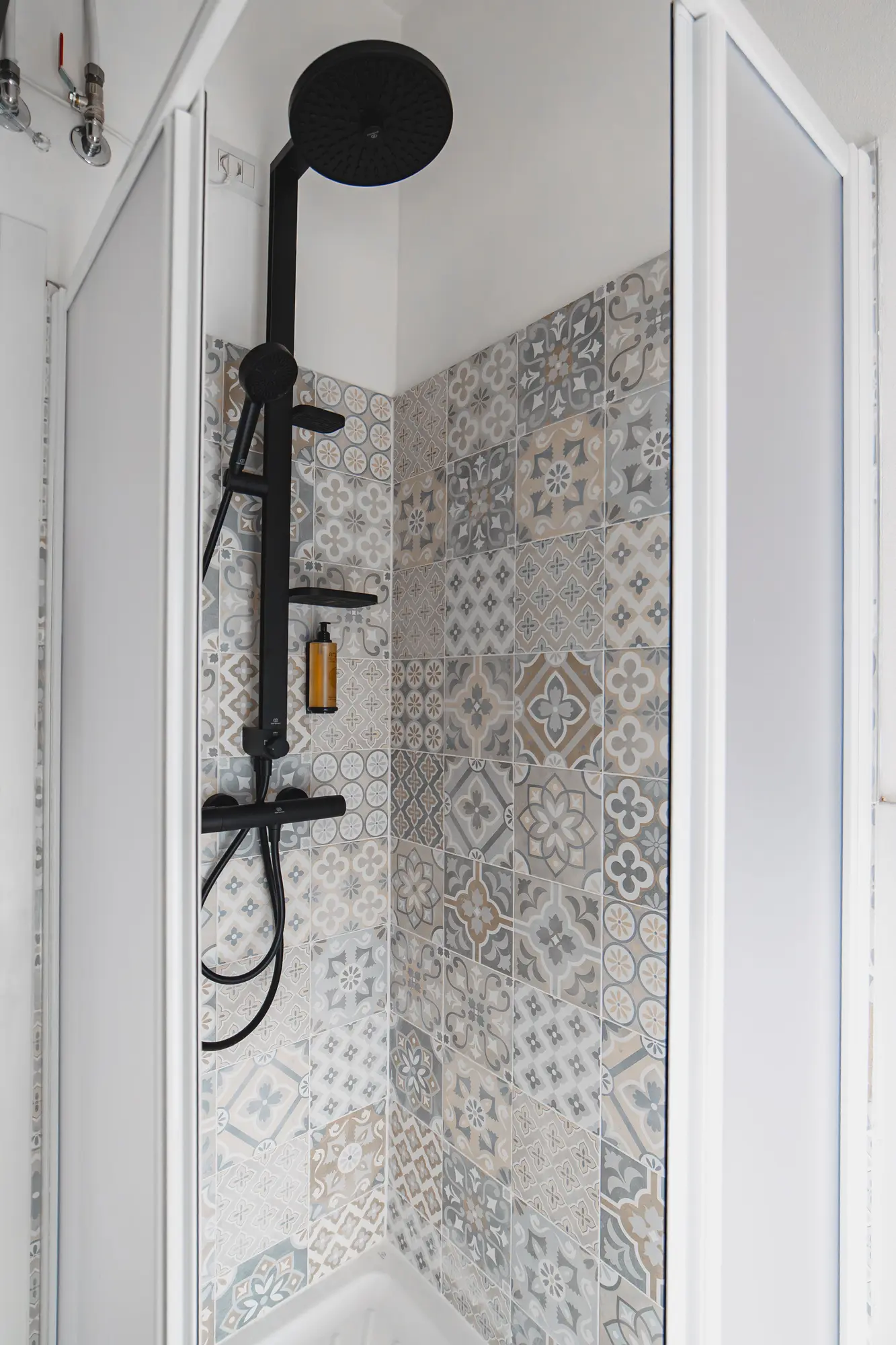 Modern walk-in shower with patterned tiles and matte black rain shower fixtures